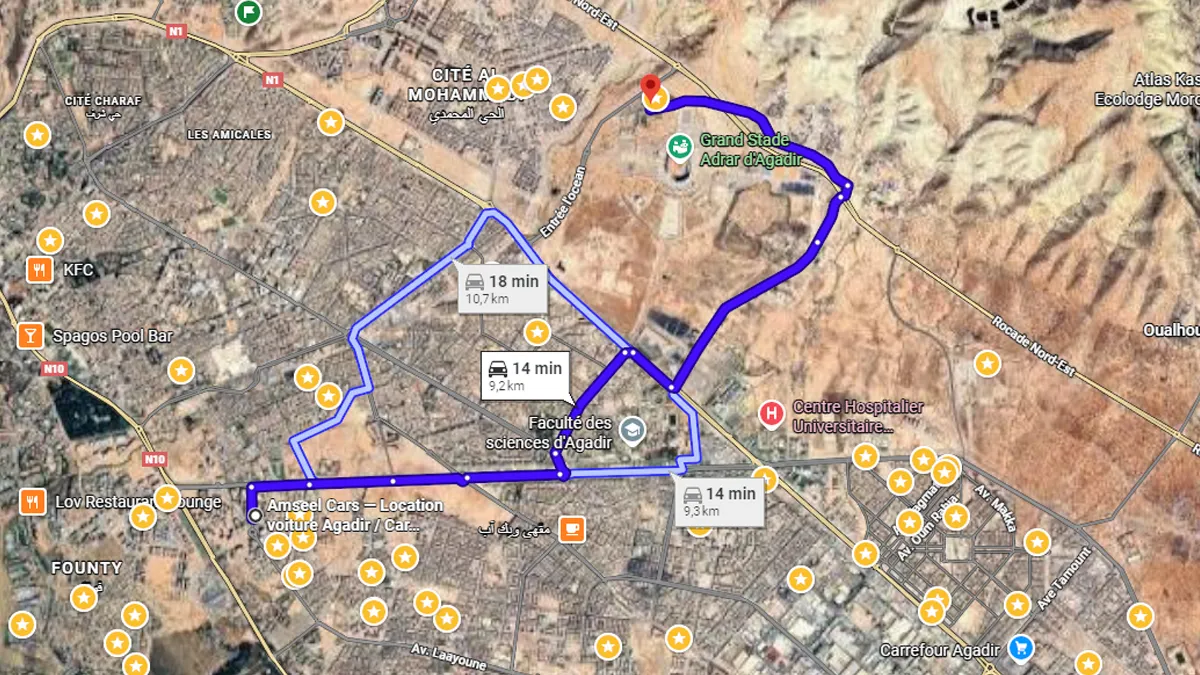 Voiture sur la route nationale N10 avec paysage verdoyant et panneau discret vers le circuit, symbolisant l’accès facile au Maroc Racing Karting Agadir.