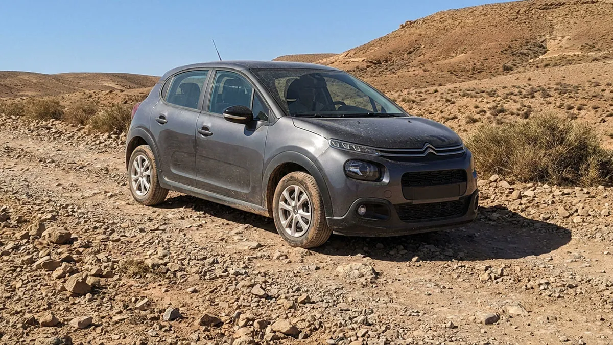 Citroën C3 Normal grise traversant une piste caillouteuse du désert d'Agafay