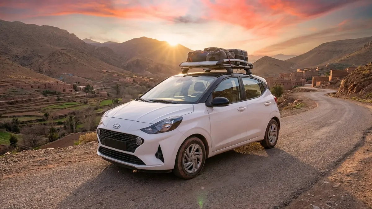 Hyundai i10 2024 avec bagages sur le toit, prête pour un road-trip sur une route montagneuse au Maroc, Hyundai i10.