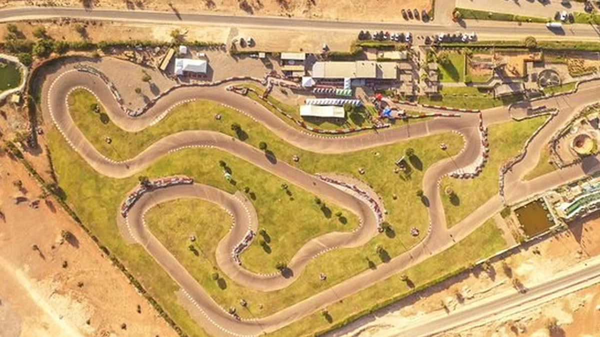 Tracé de la piste avec ses virages techniques, éclairage LED, zone de détente avec lounge et karts stationnés, illustrant les installations du Maroc Racing Karting Agadir.