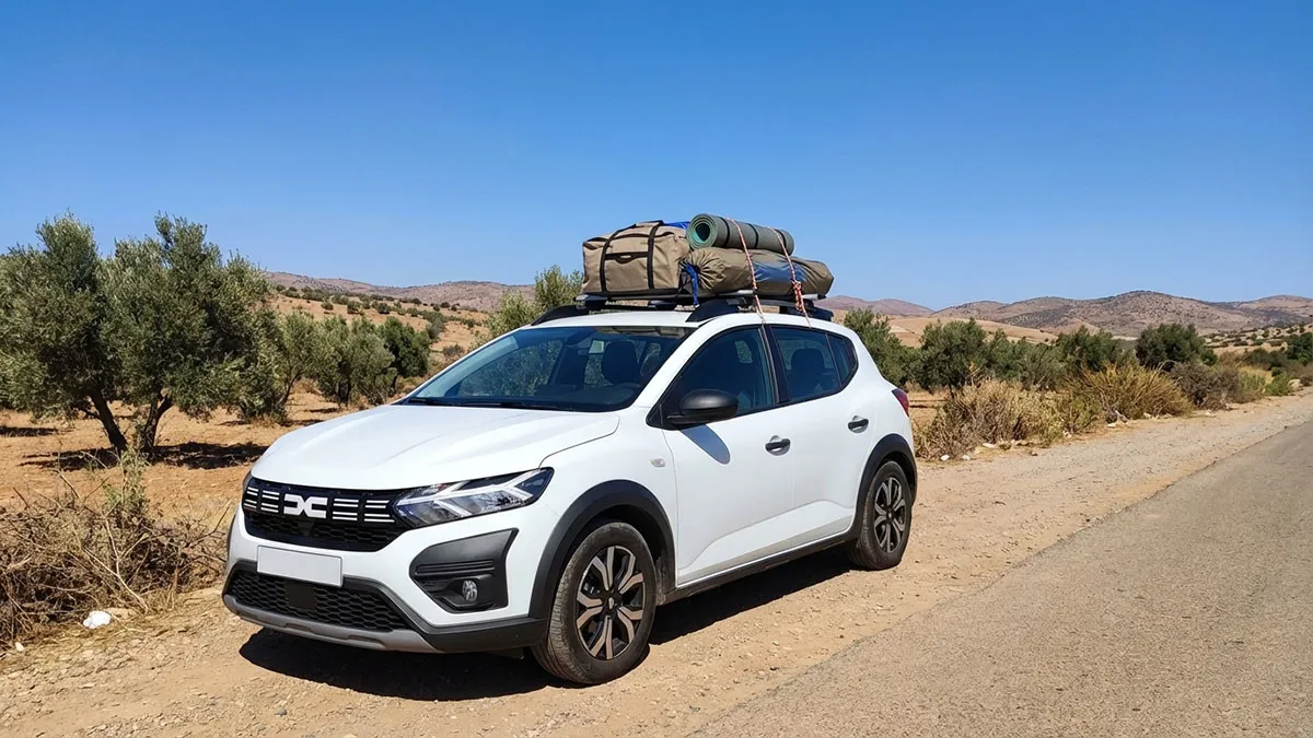 Dacia Sandero Stepway avec porte-bagages chargé de matériel de camping sur une route de campagne au Maroc, sans texte dacia sandero Stepway