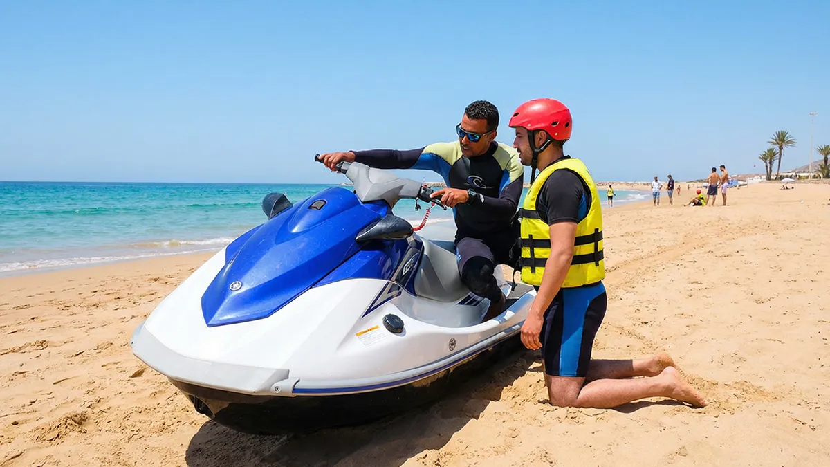 Apprenti sur un jet ski près du rivage d’Agadir, portant un casque et un gilet, écoutant attentivement un instructeur, démontrant les règles de sécurité pour le jet ski