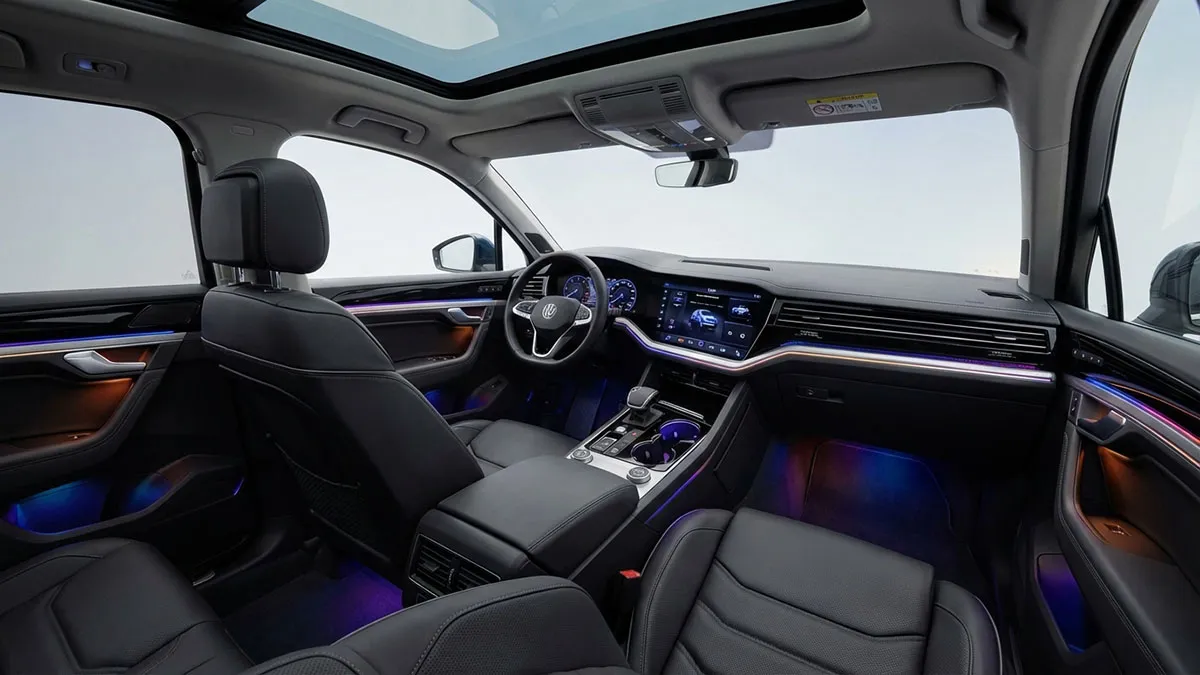 Intérieur luxueux d’un Volkswagen Touareg 2025 avec cuir Nappa beige, inserts en aluminium brossé et éclairage d’ambiance multicolore dans l’habitacle.
