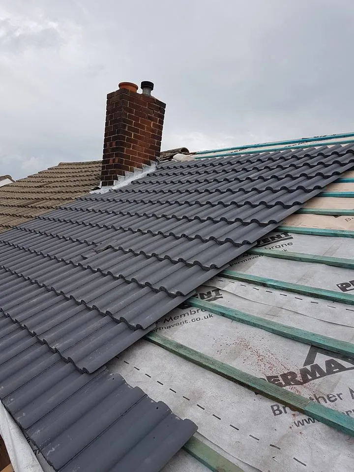 Re-roofing process showing new roof tiles, underlay, and battens being installed next to a chimney.