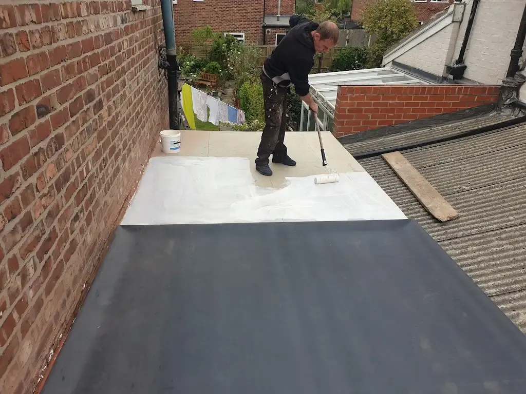 Roofer applying white coating to a flat roof