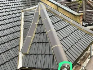 Tiled dormer roof section with dark grey tiles and lighter grey cappings.