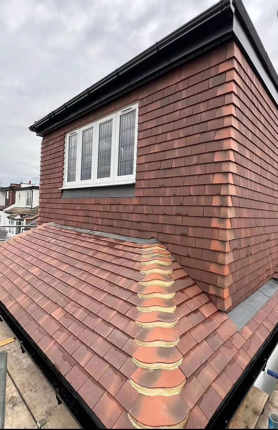 Newly installed terracotta-tiled roof and dormer on a house, showcasing quality workmanship.