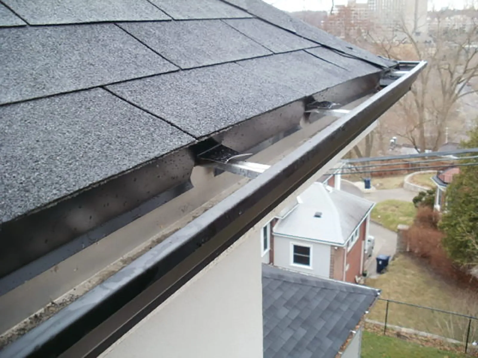 A close-up view of a blocked gutter on a residential roof.