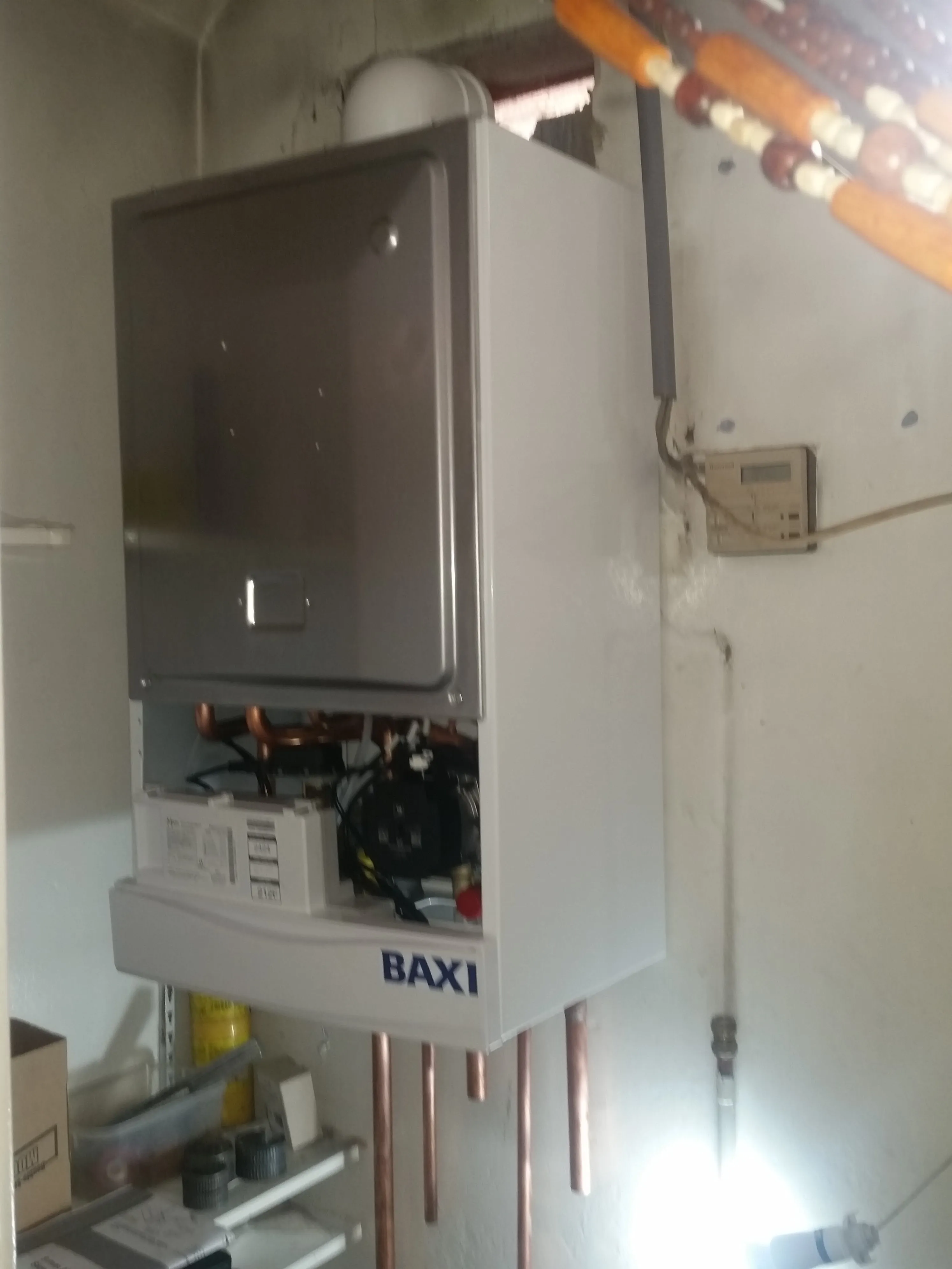 A new or recently installed Baxi boiler with its internal workings and copper pipes visible, possibly undergoing installation or service.