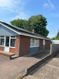 A bungalow with a tiled roof, solar panels, and a clean roofline, representing domestic roofing services.