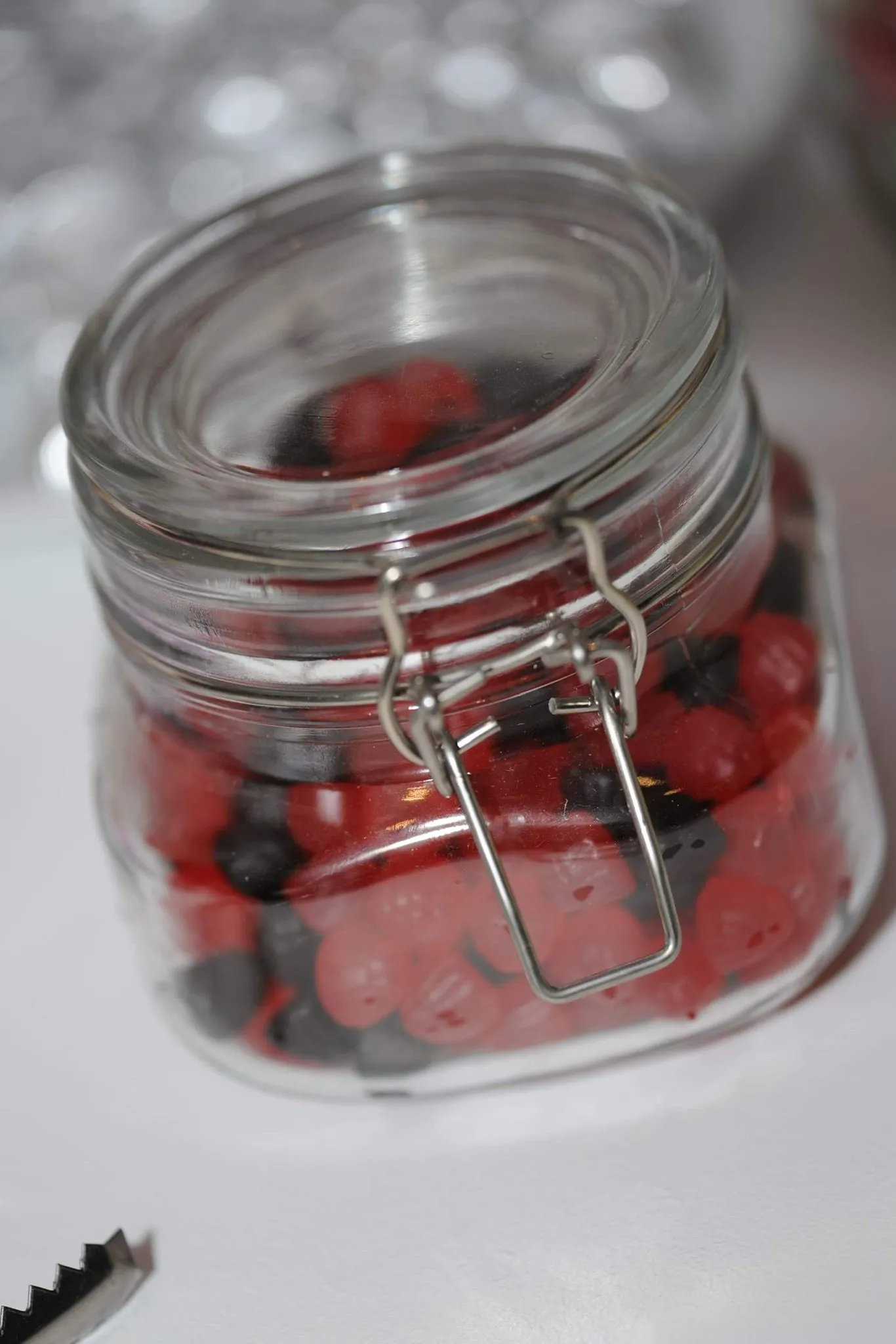 Glass jar filled with red and black sweets, for a candy cart or sweet table hire