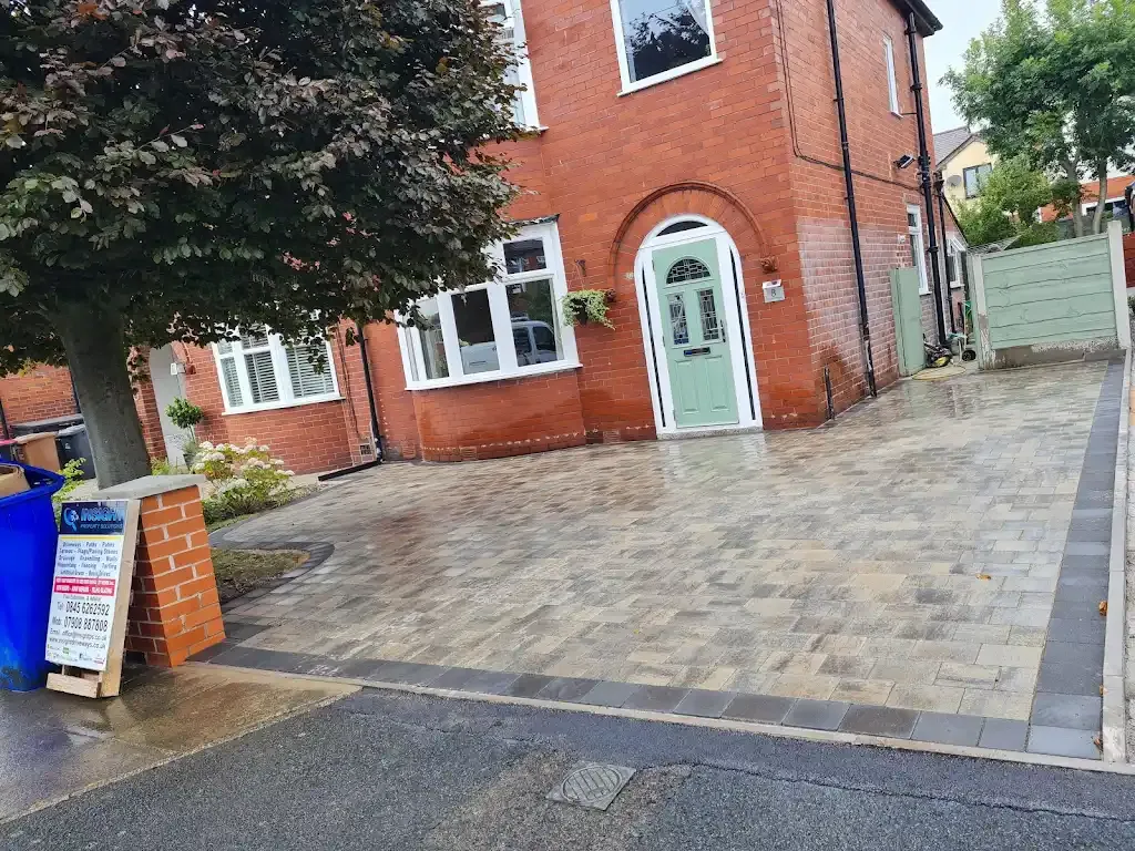 Newly laid block paving driveway in front of a red brick house with a green front door.
