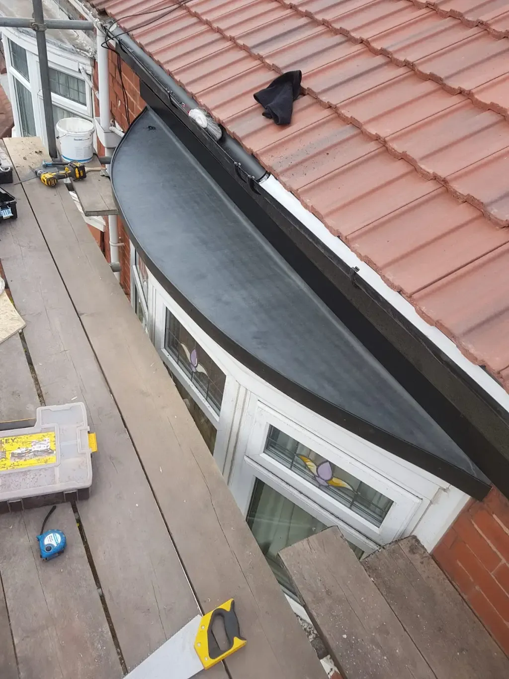 Scaffolding and tools on a residential roof during repair or installation work on a flat roof section.