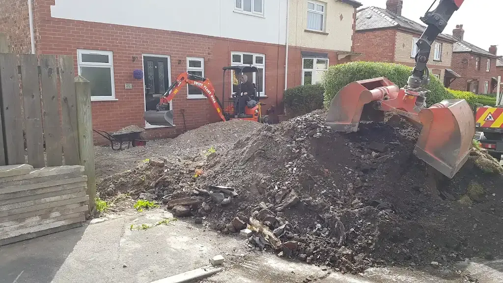 Two diggers excavating soil during groundwork at a house.