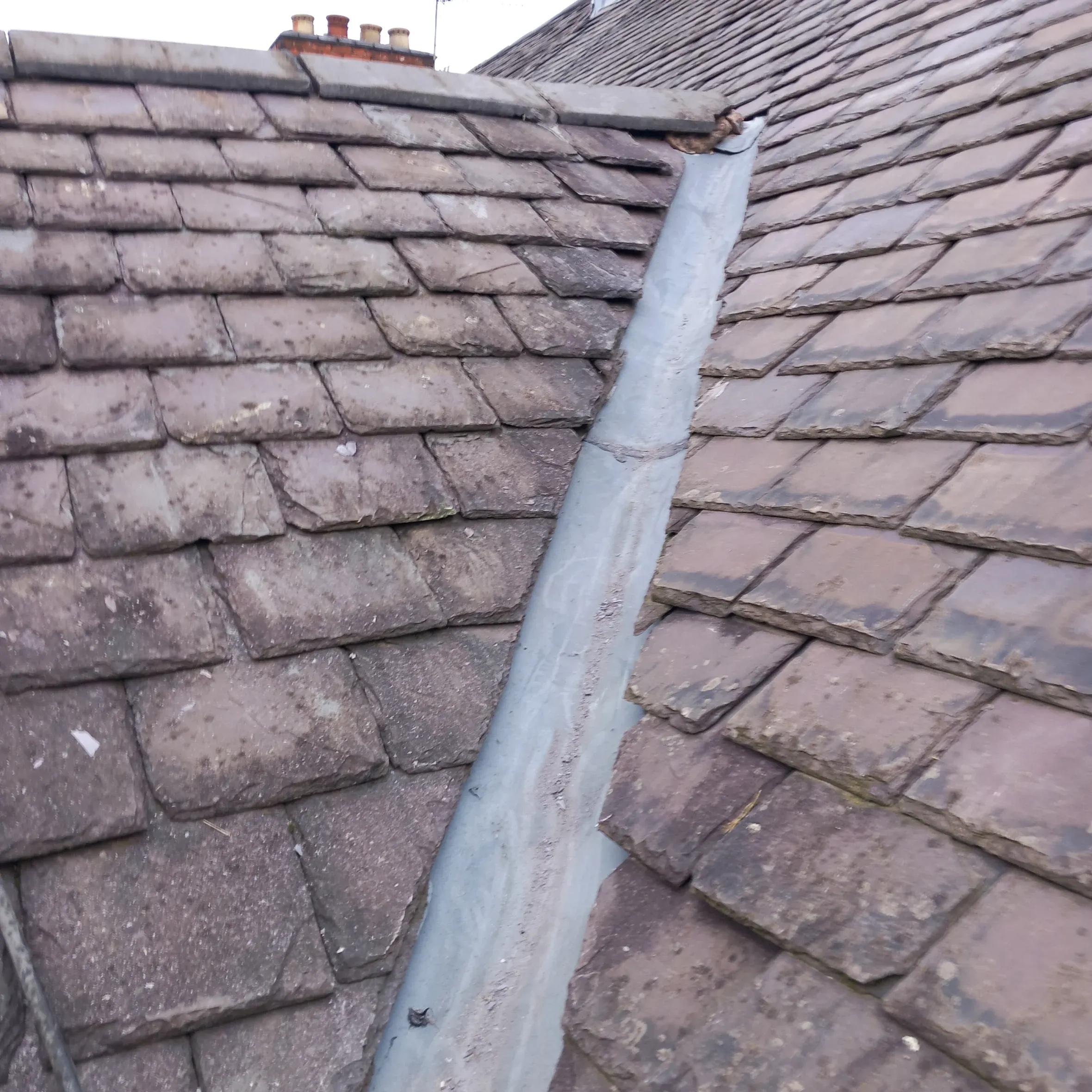 Slate and tile roof with weathered lead valley and moss, showing repair needs for Leicester homes. 5 Star Roofing Leicester are local experts for roof repair, leadwork, and moss removal in Leicestershire.