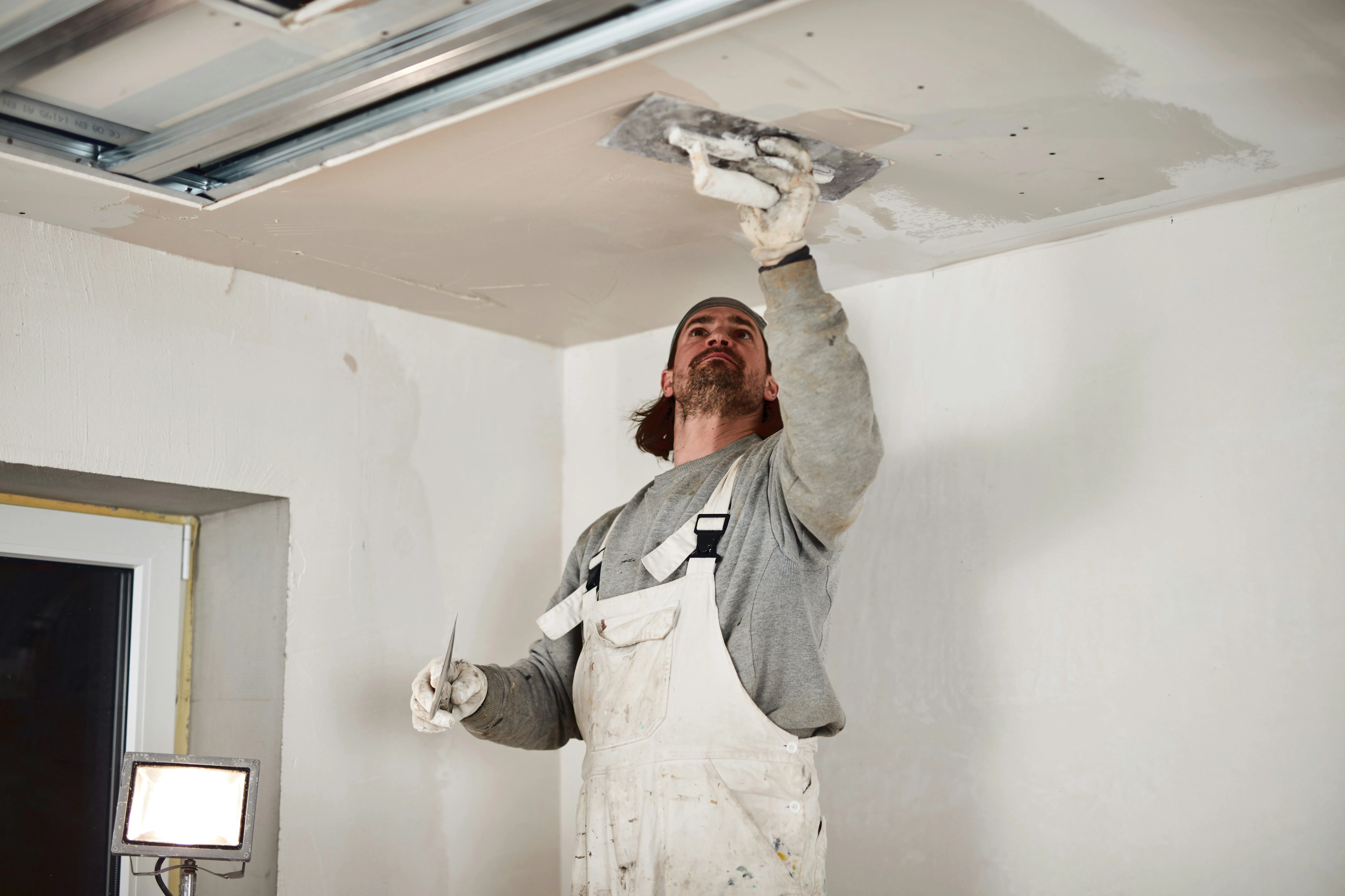 Professional plasterer working on a ceiling during a renovation in Haywards Heath, West Sussex.