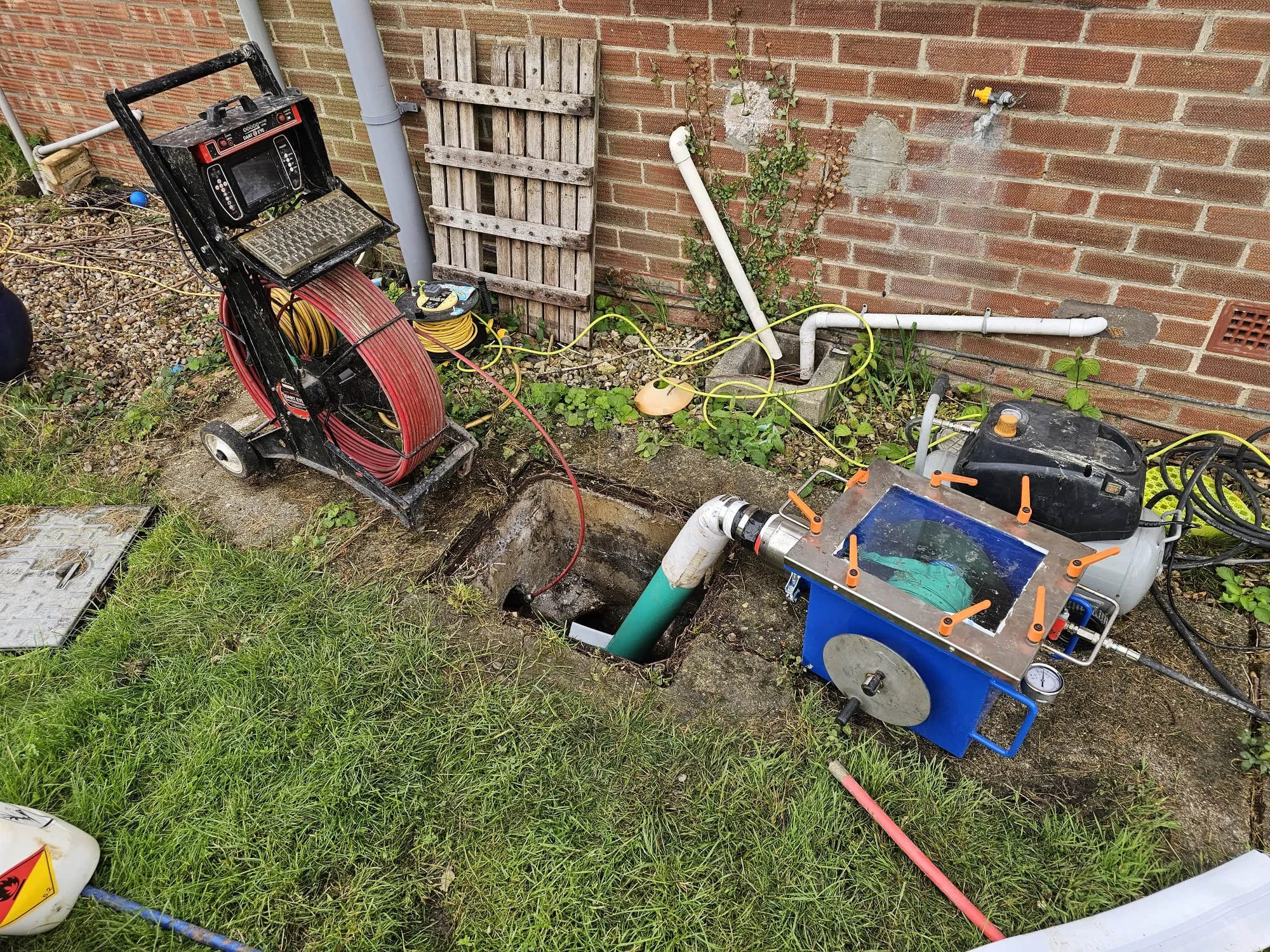 CCTV drain survey camera and drain relining equipment set up at an open manhole for pipe inspection and no-dig repair.