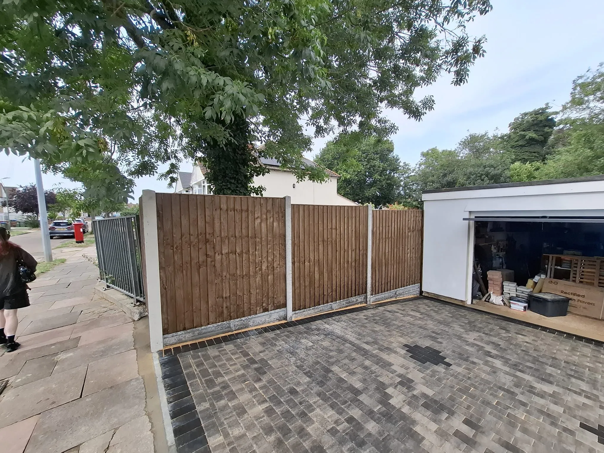 Newly laid block paving driveway with a modern pattern and a new wooden garden fence.