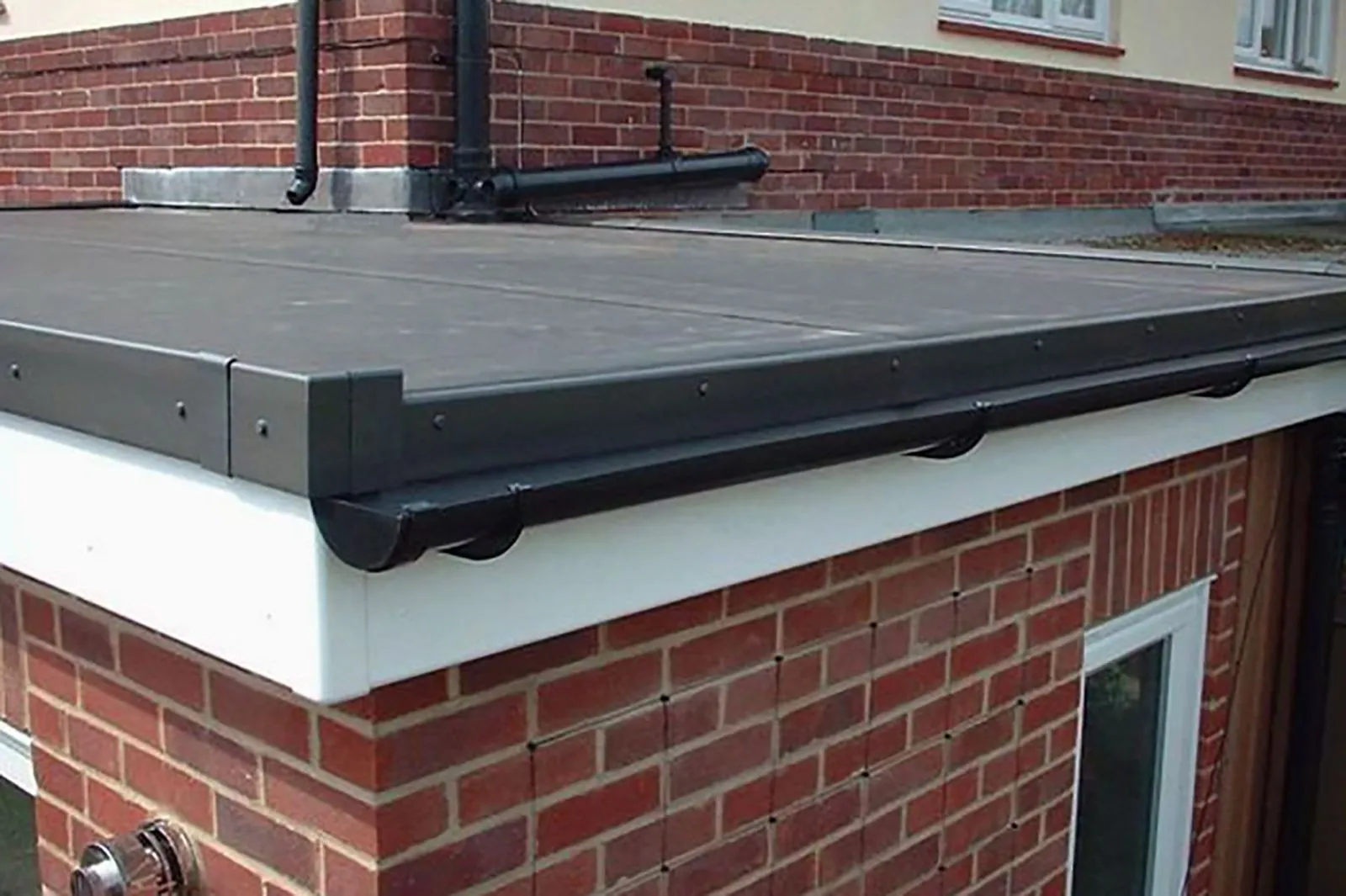 New flat roof with black guttering and white fascias on a brick extension in Haywards Heath.