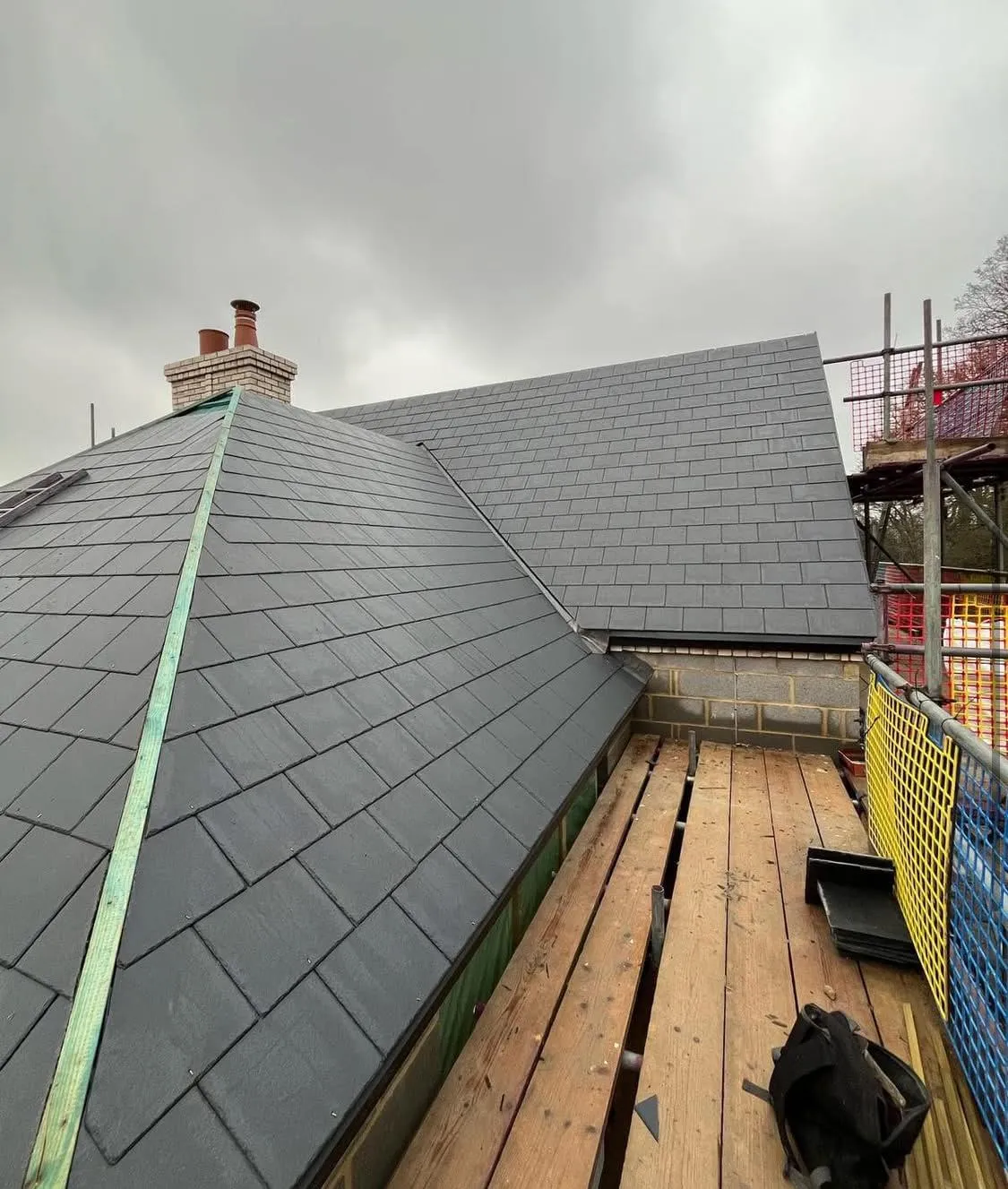 High-quality new slate roof installation with chimney stack and scaffolding by Devon and Cornwall Roofing.
