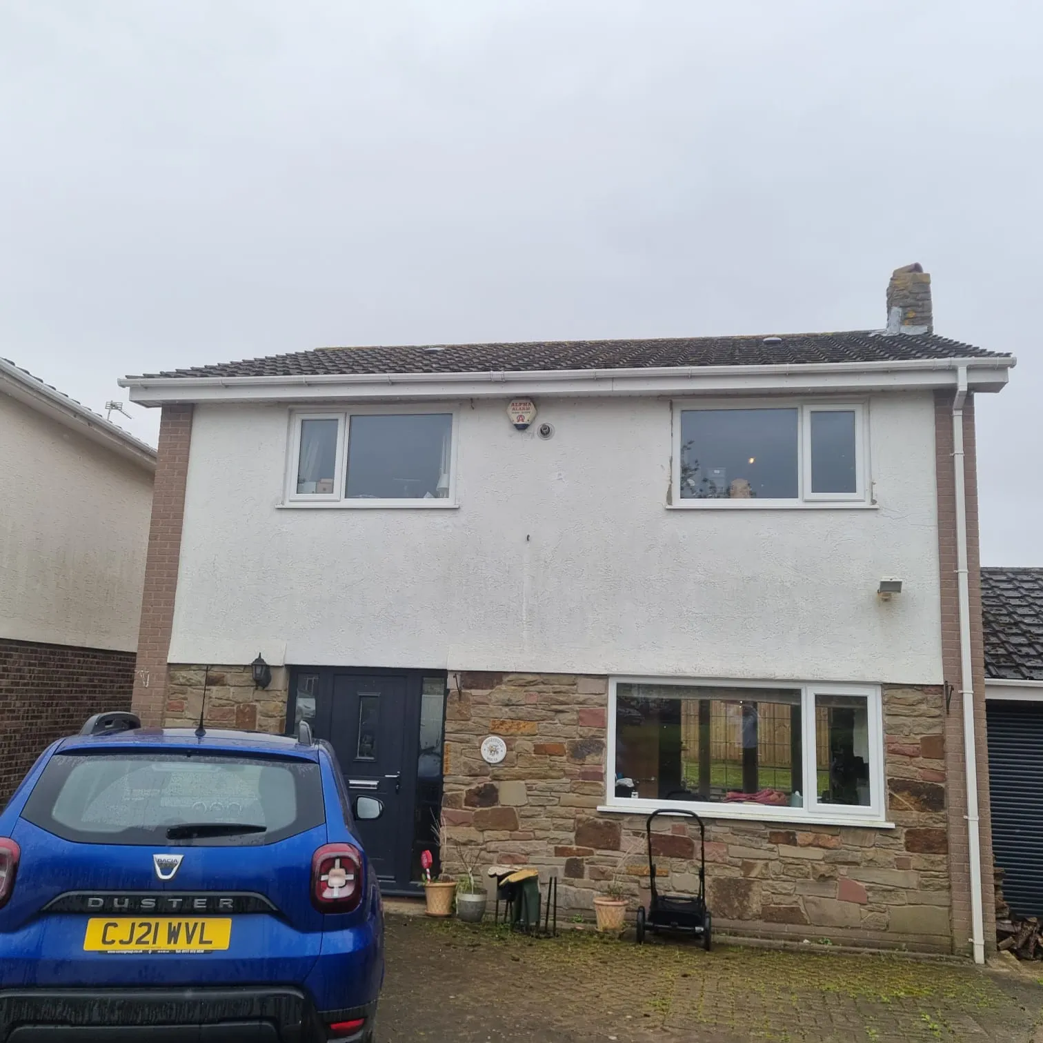 Front view of a modern house showcasing its tiled roof, white gutters, fascias, and clean exterior, representing a completed roofing and guttering project.