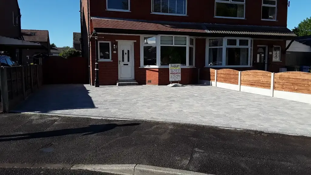 A picture of a recently completed grey block paved driveway and new wooden fence at a residential property.