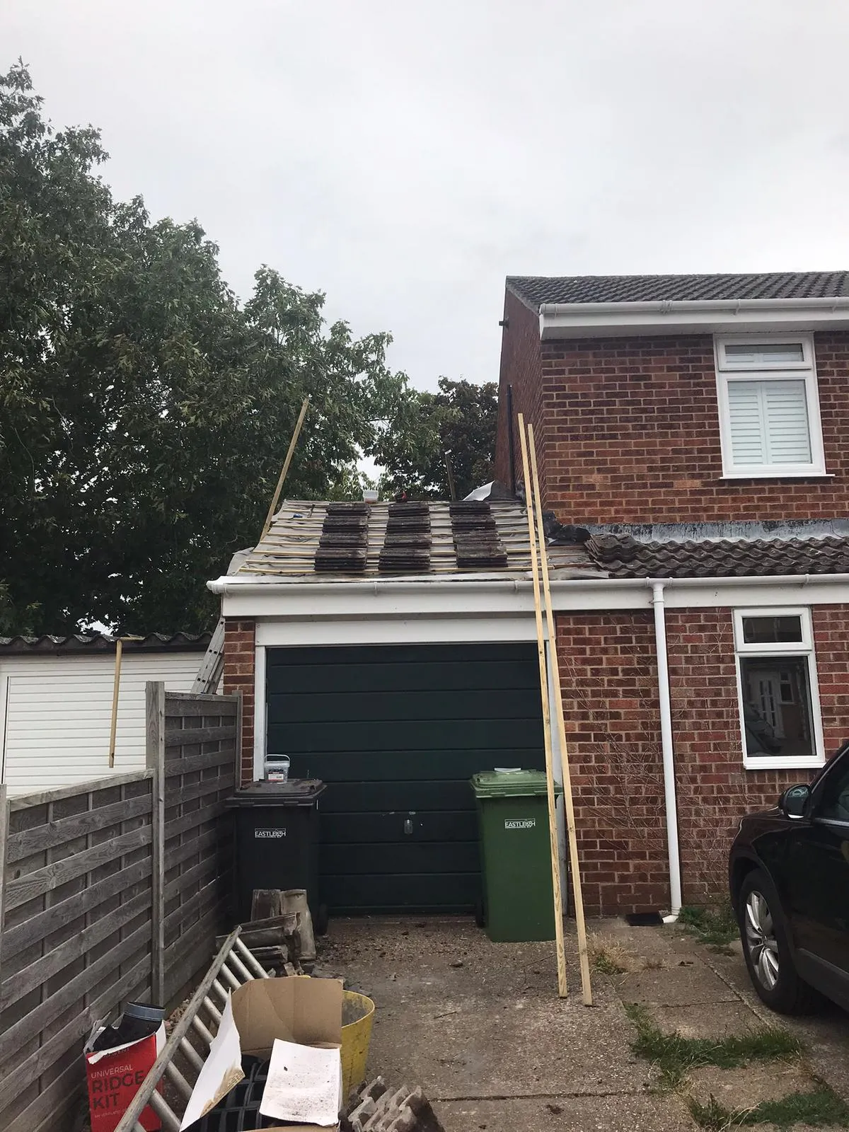 A garage roof being repaired or re-tiled, showing new tiles, underlayment, and construction materials on a residential property in Southampton.