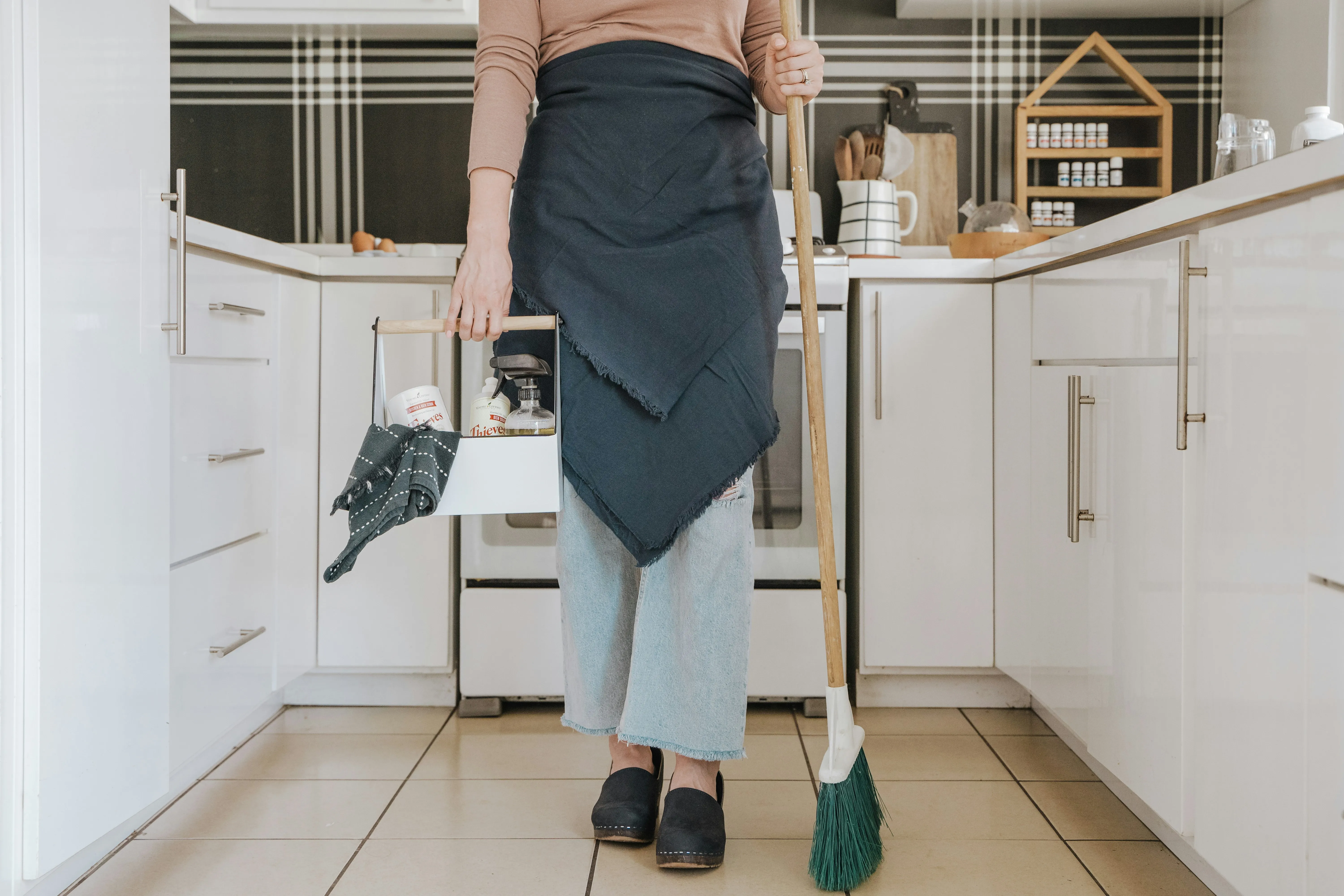 Professional cleaner with eco-friendly supplies in a bright kitchen.
