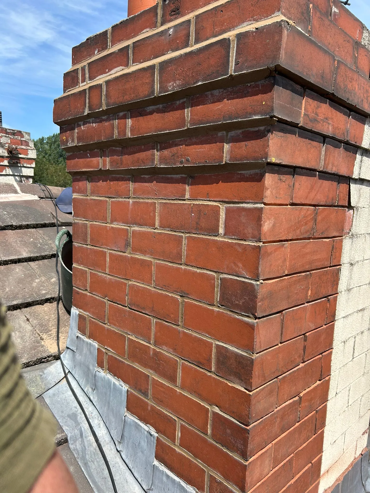 A brick chimney with professional lead flashing on a residential roof.