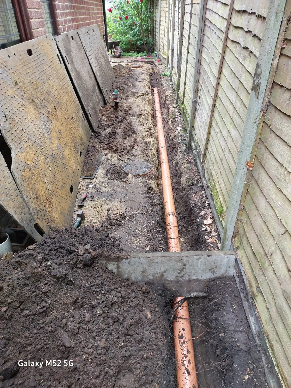 New drainage pipe installation in an excavated trench next to a house
