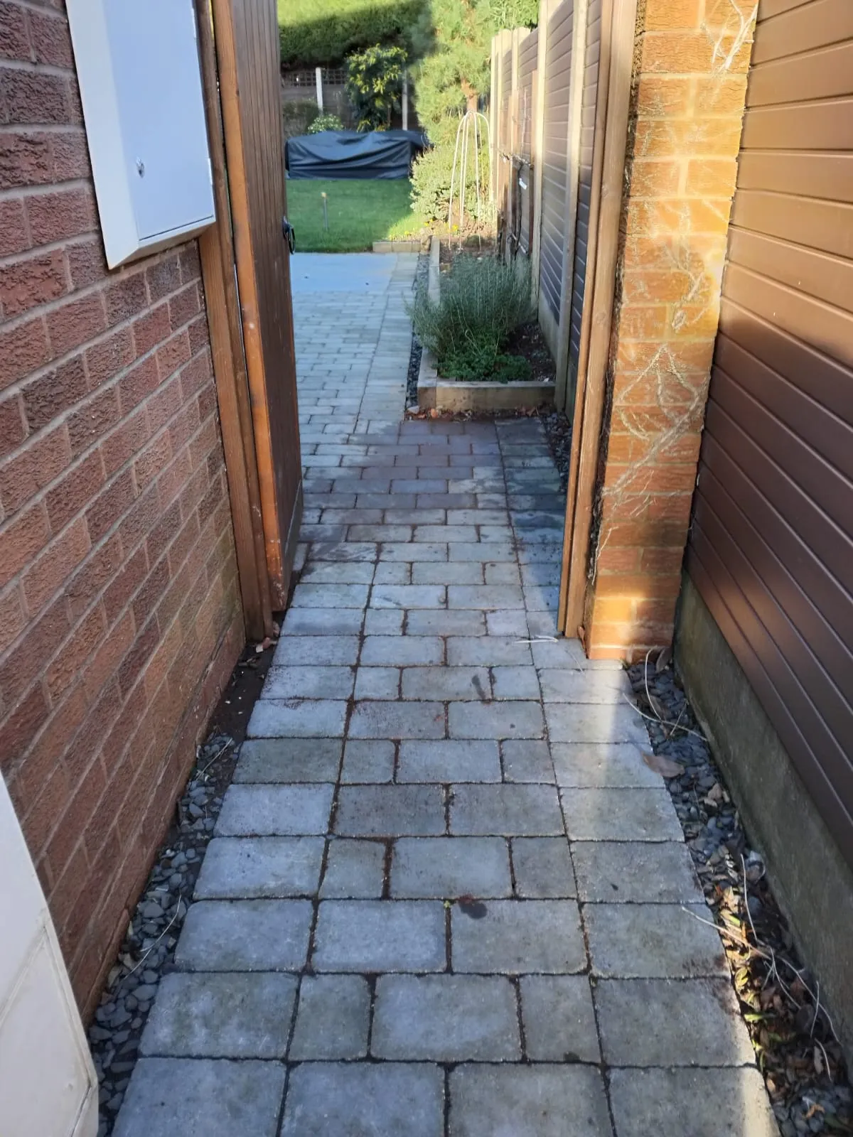 Block-paved pathway with wet patches, suggesting a drain leak, overflow, or poor surface water drainage.