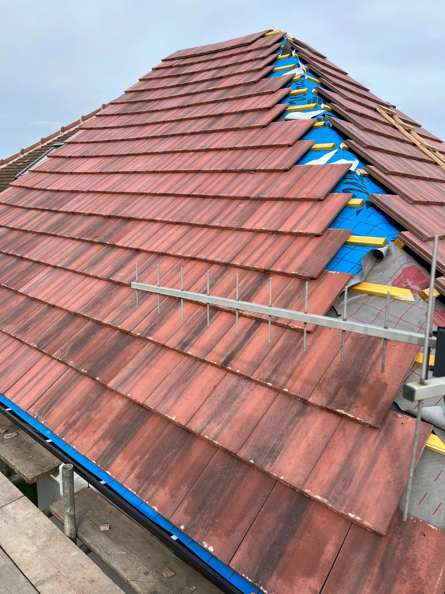 Professional new roof installation underway with tiles, underlay, and battens visible