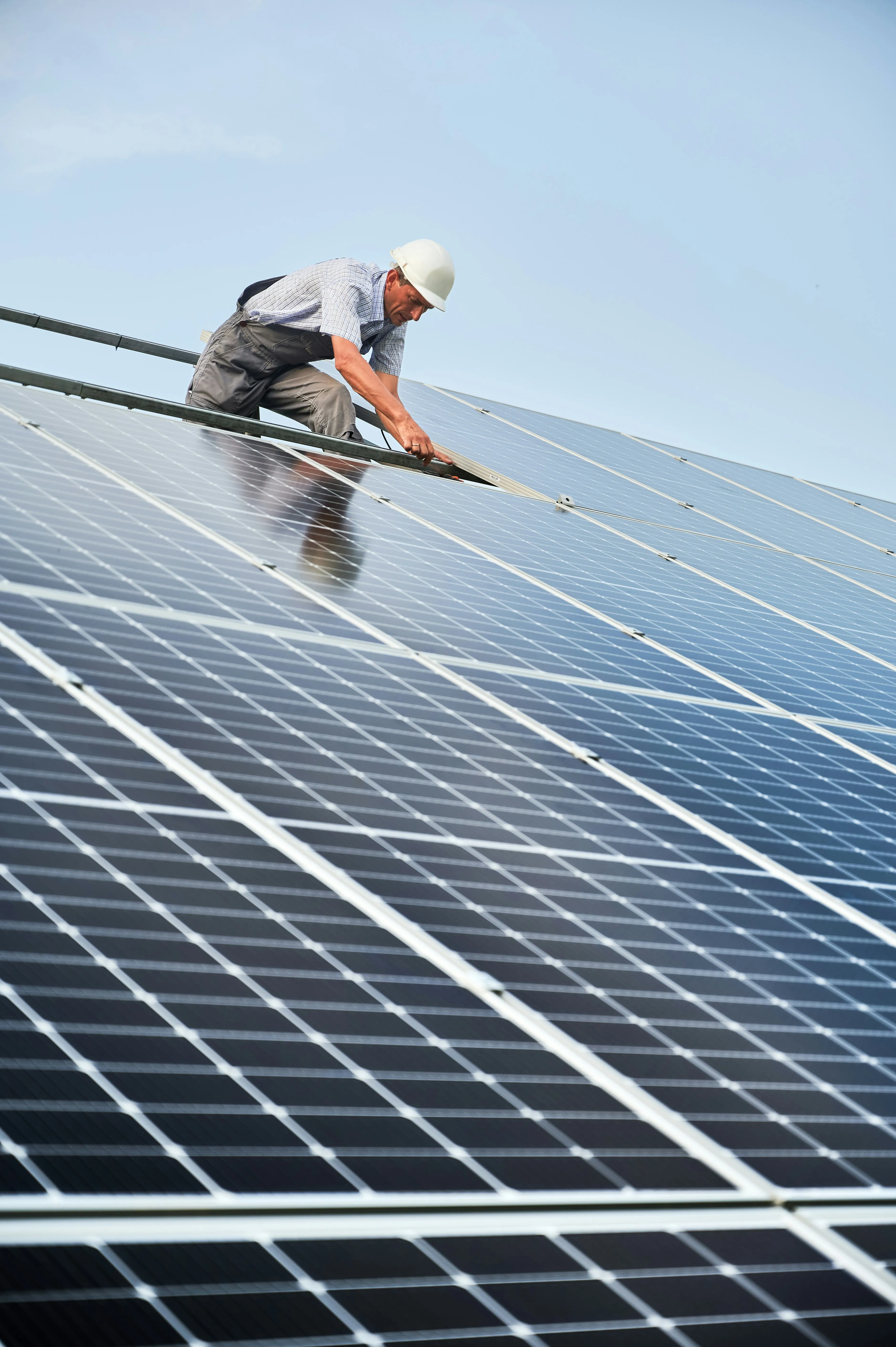 An electrician installing solar panels on a rooftop, connecting the modules for a renewable energy system.
