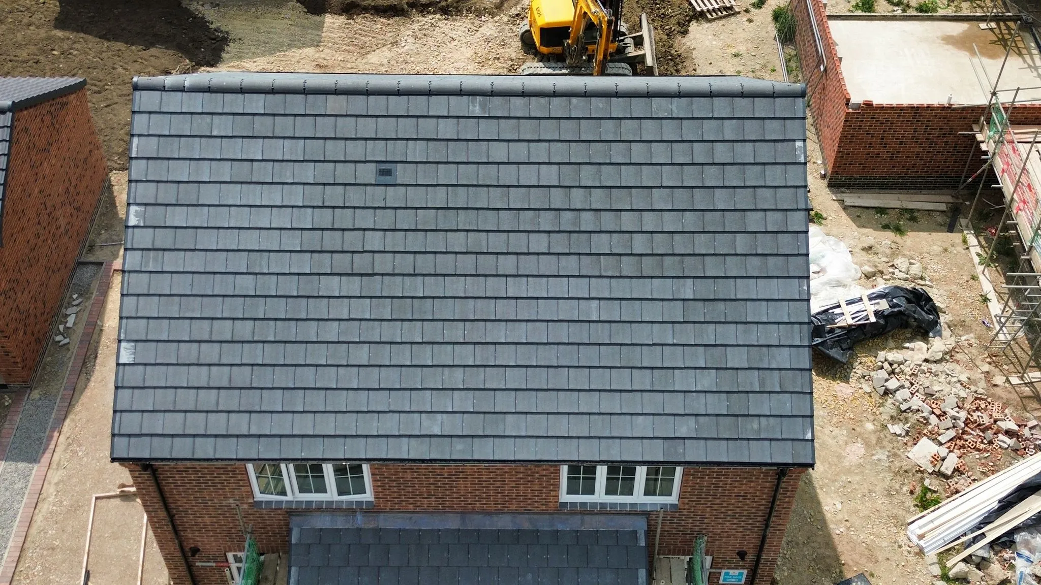 Aerial view of a new pitched roof installation with modern dark grey tiles on a residential home, showcasing quality roofing work by Foster and Son Roofing Services in Spalding or Peterborough.