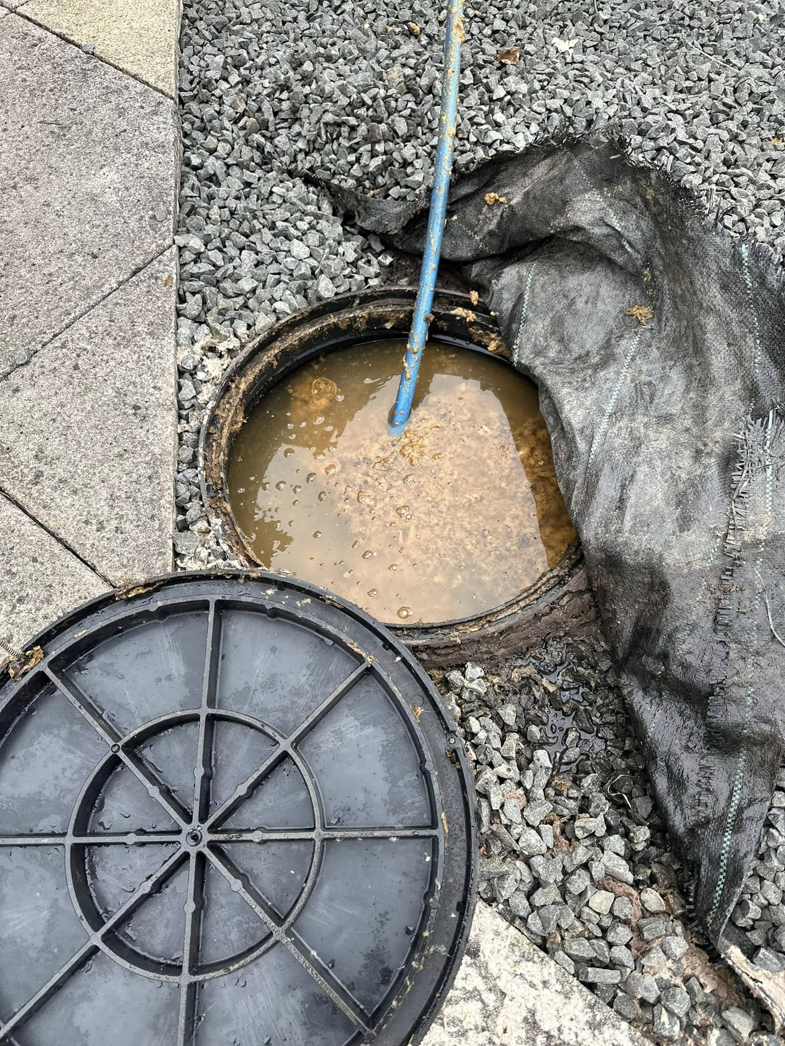 Blocked drain access point with dirty water and a drainage rod during unblocking work by Drain 2 Flow Exmouth.