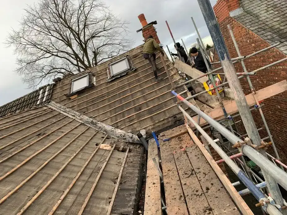 Roofers on scaffolding replacing a pitched roof with exposed wooden battens