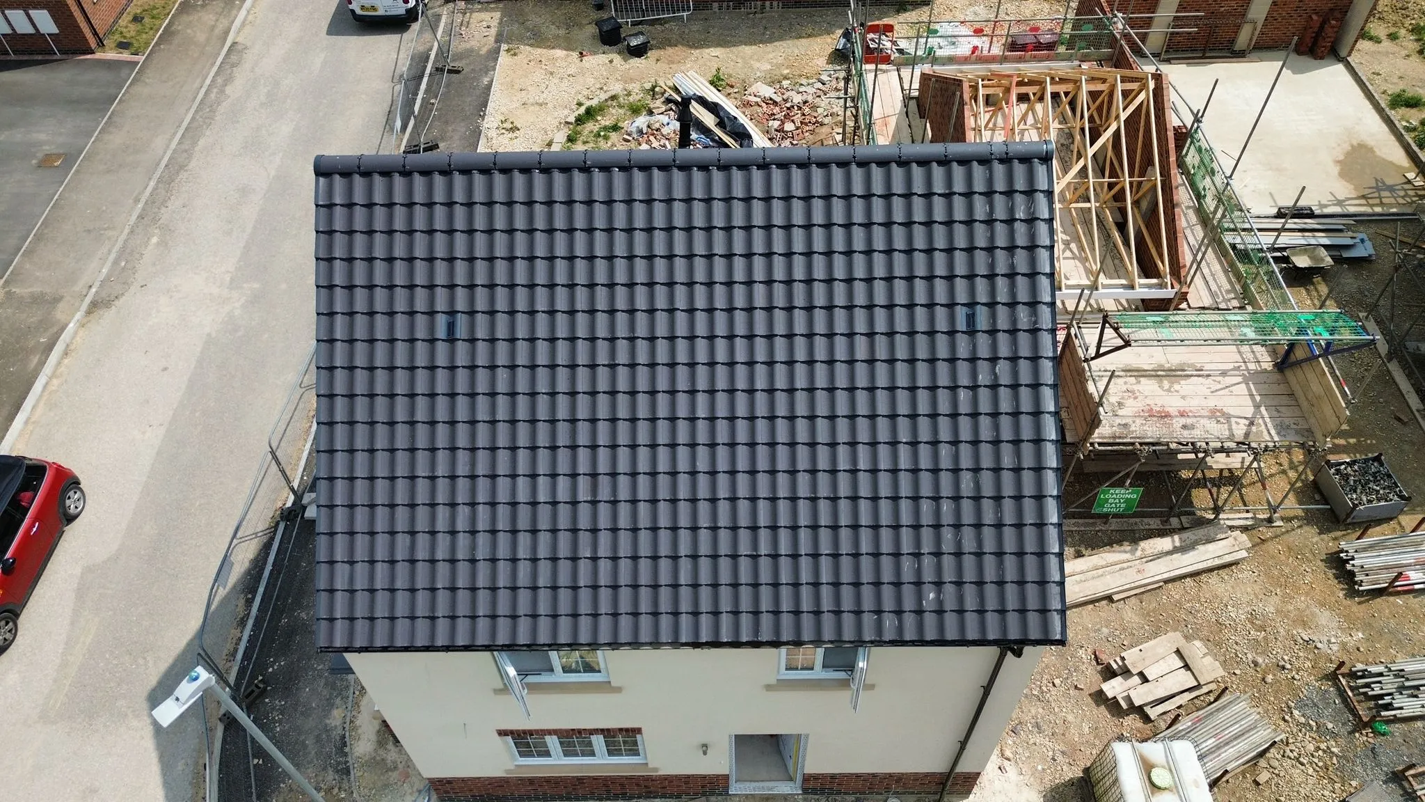 Aerial view of a new pitched roof with dark grey concrete tiles on a house construction site in Spalding or Peterborough.