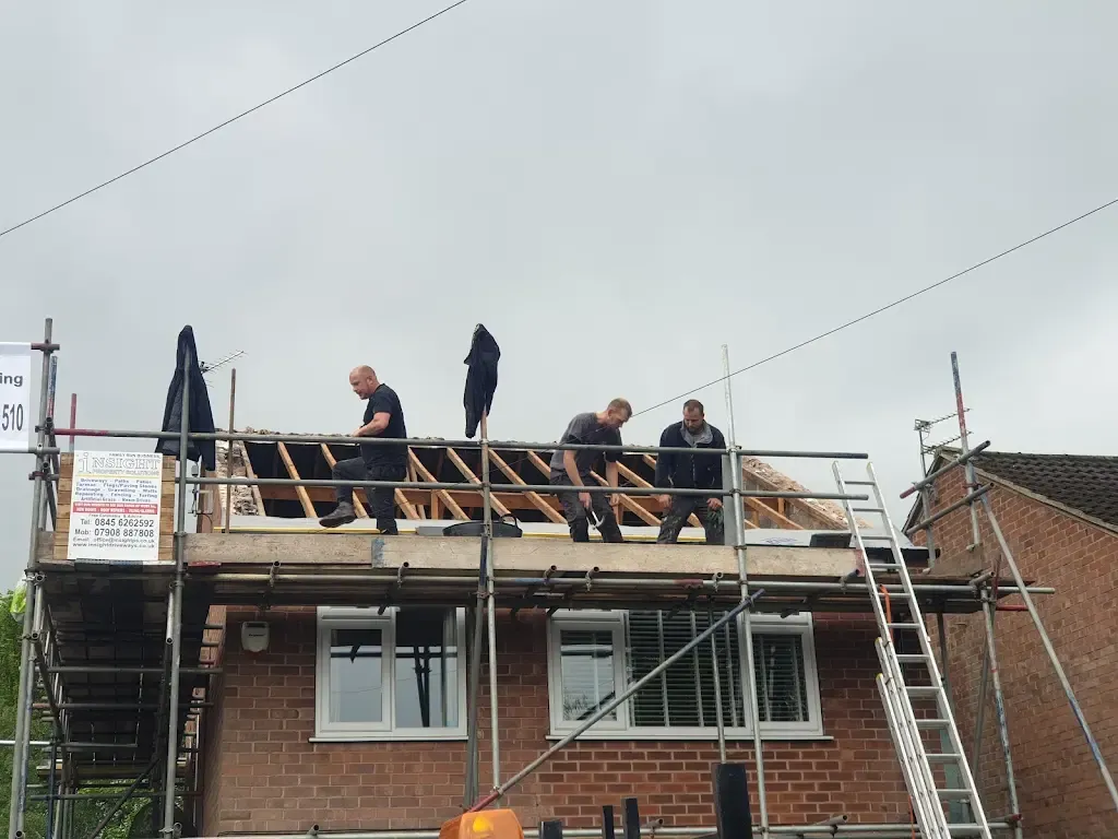 Three roofers on scaffolding working on a residential roof repair or replacement