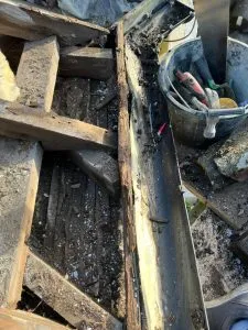 Damaged roofline with rotten wood, exposed roof structure, and a dirty gutter in need of repair or replacement.