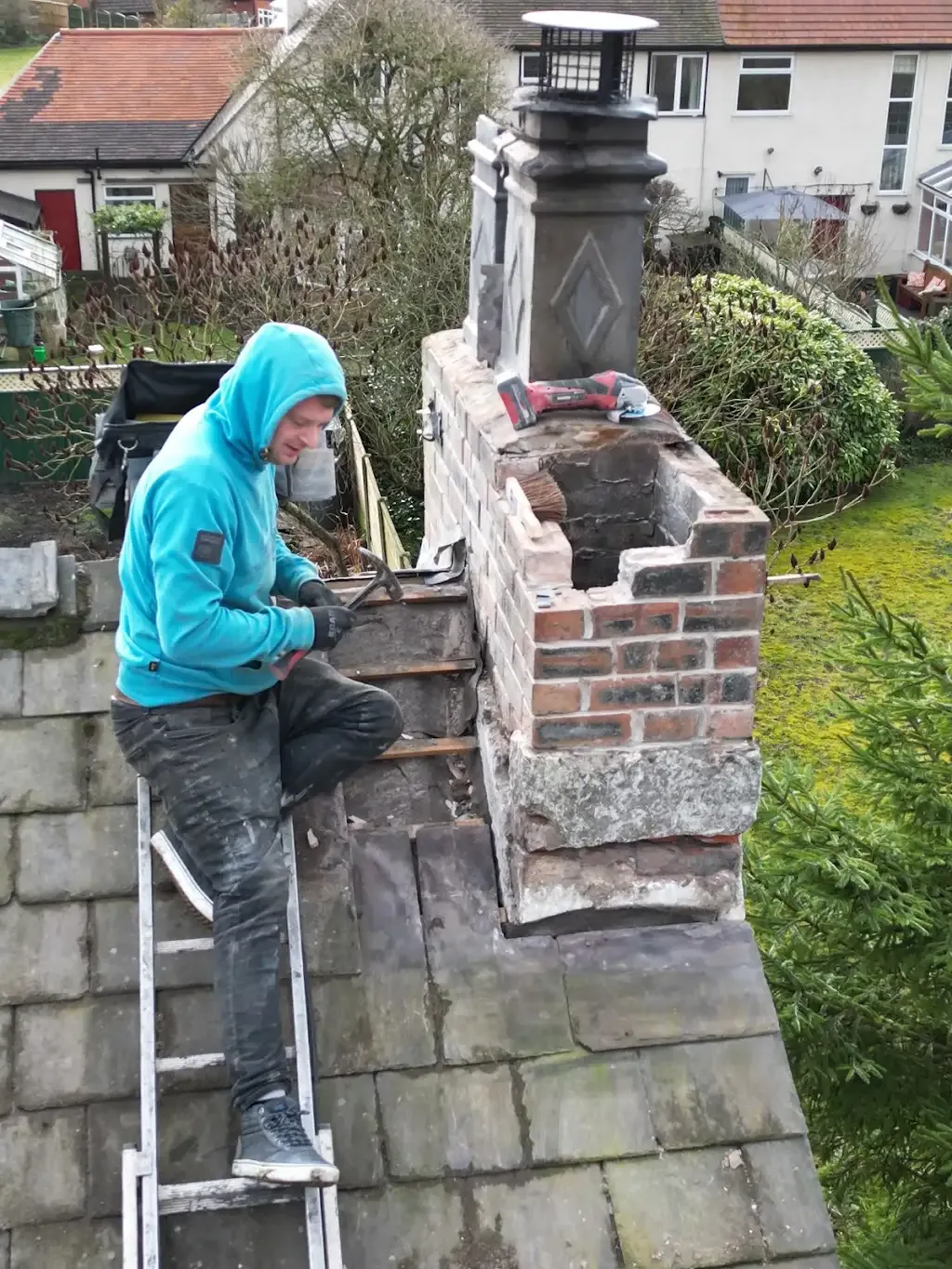 Experienced roofer repairing a chimney on a slate roof in Manchester