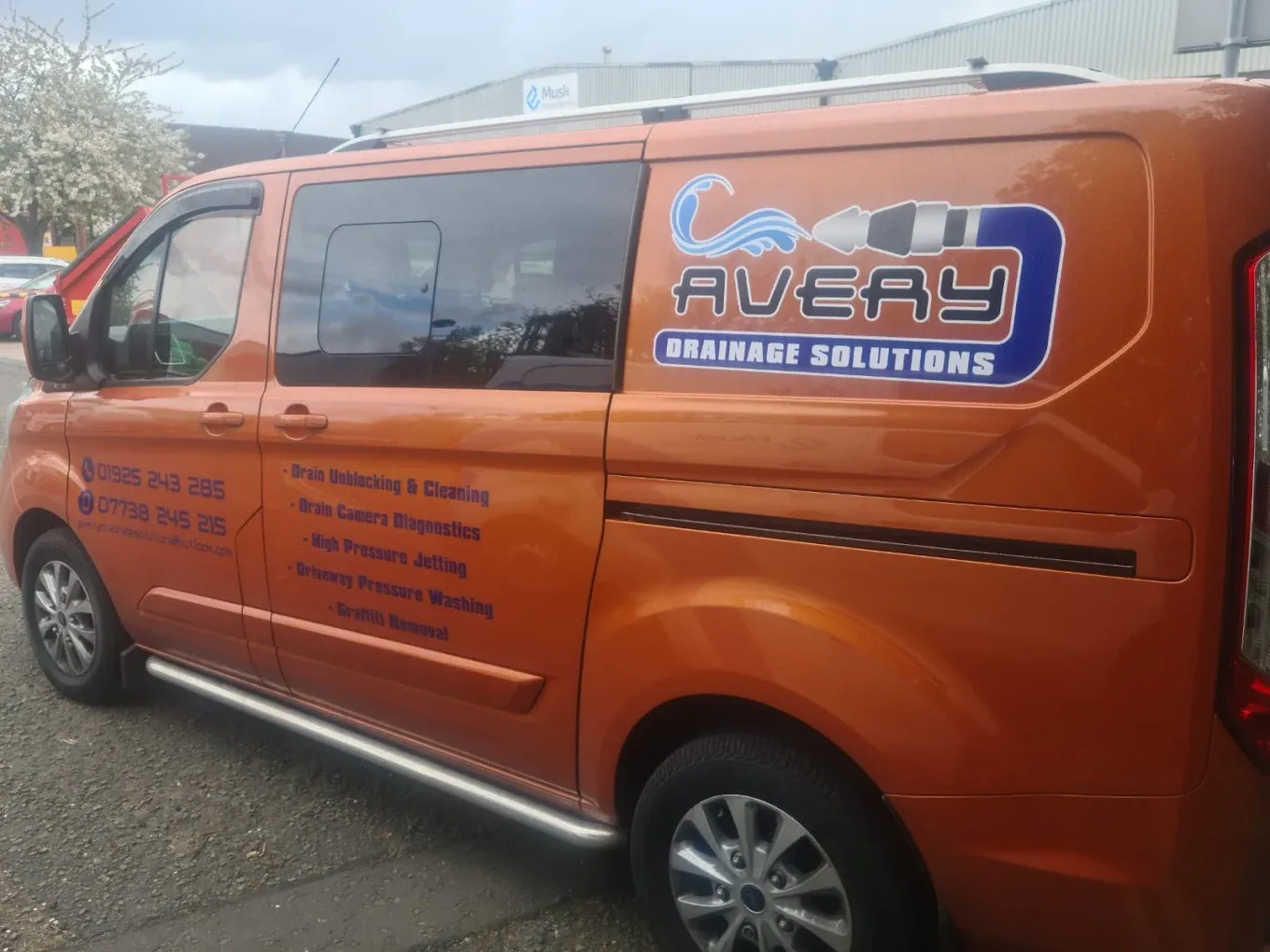 Orange Avery Drainage Solutions van showing logo, phone numbers, and services like drain unblocking, CCTV surveys, and high pressure jetting.