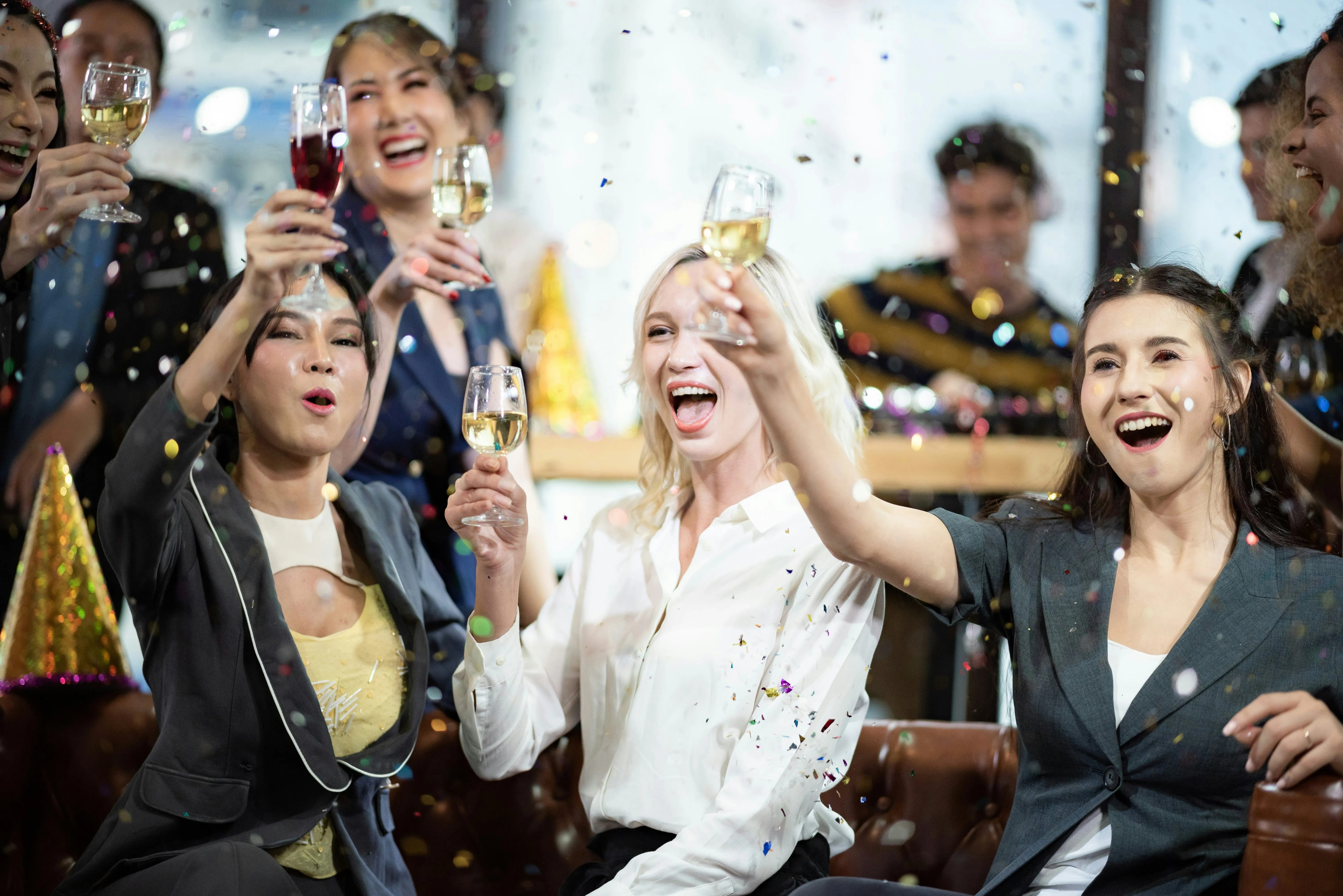 Joyful guests raising glasses with confetti falling at a lively corporate event or celebration.