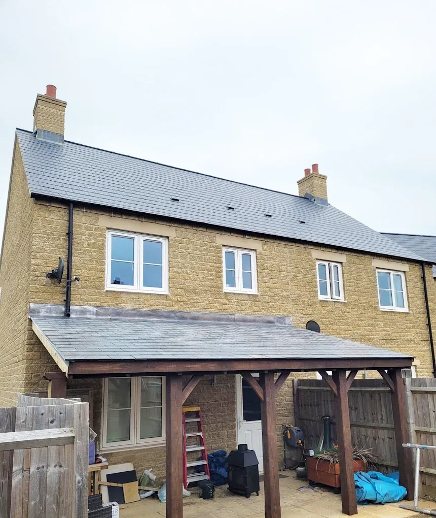 Newly completed slate pitched roof installation on a stone residential property, including a matching slate lean-to roof.