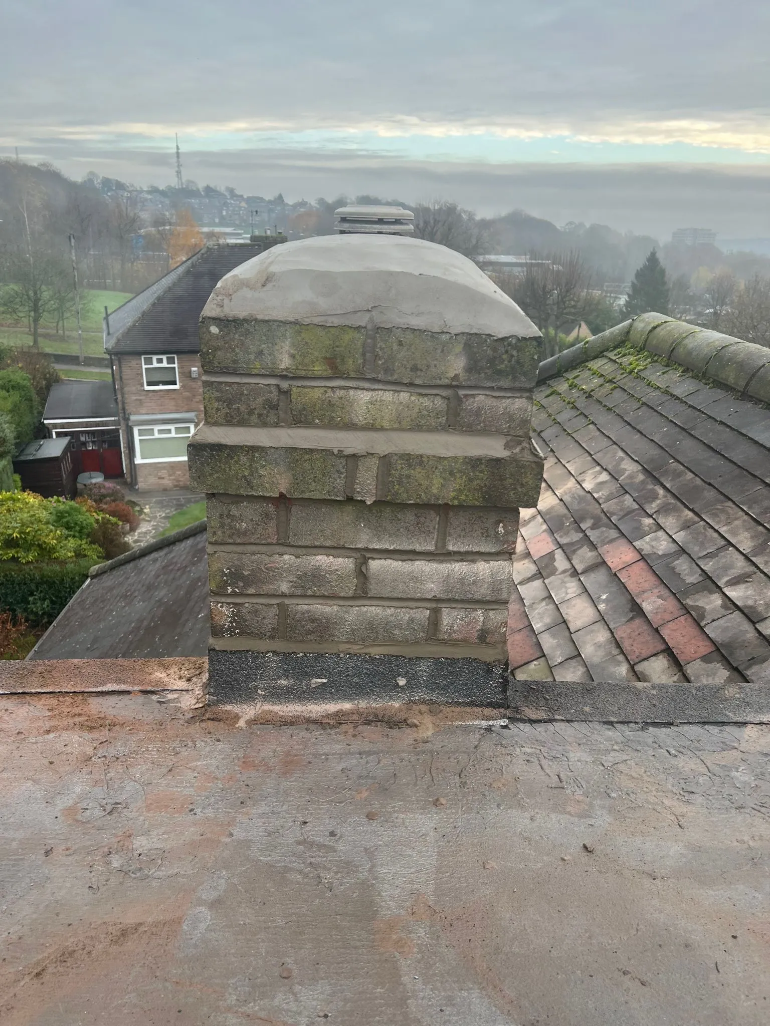 A brick chimney on a pitched roof with Sheffield and Peak District views