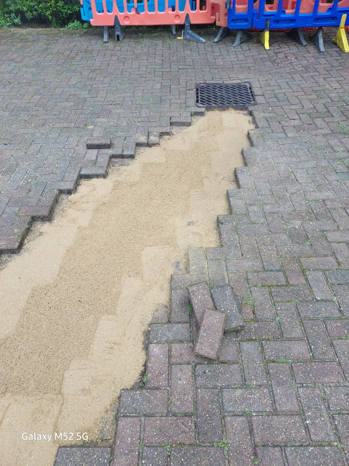 Excavated storm drain with removed block paving for repair or installation on a driveway.