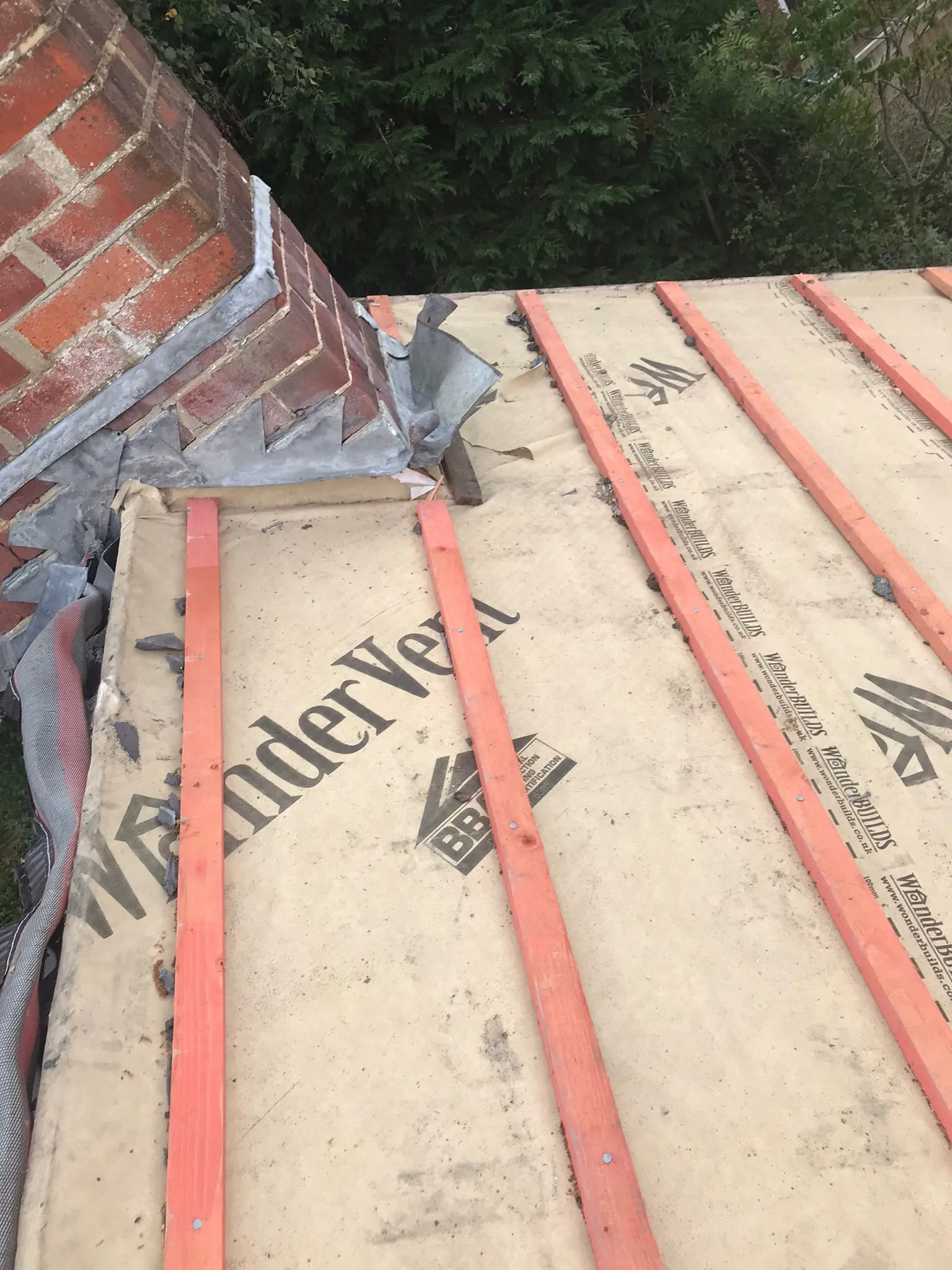 Detailed view of roof construction with chimney lead flashing and timber battens on a roofing membrane.
