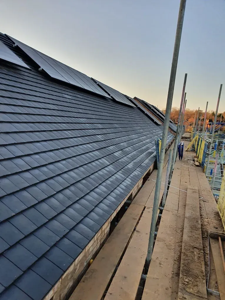 New tiled pitched roof installation with solar panels and scaffolding.