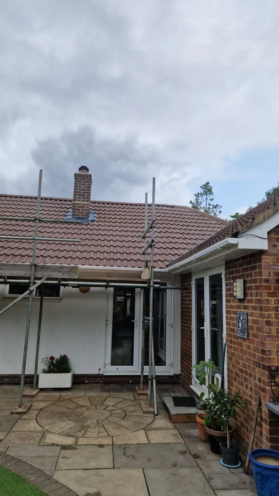 New red tiled pitched roof installation with scaffolding on a residential home by Trustmark Roofing.