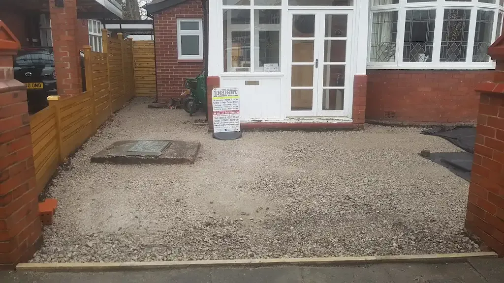 Groundwork preparation for a new driveway installation by Insight PS, showing gravel sub-base, drain cover and new fencing.