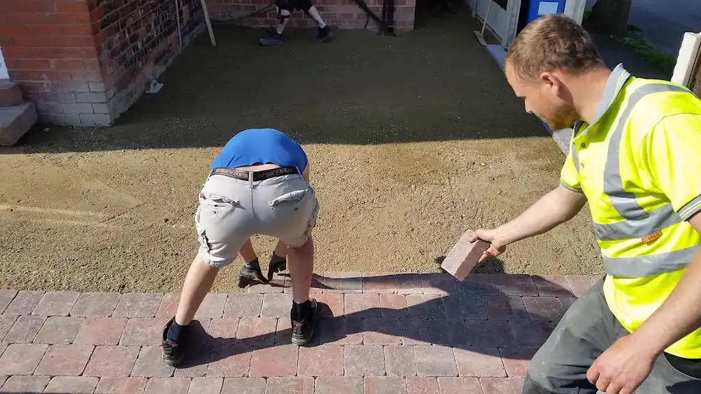 Workers installing block paving bricks for a driveway in Manchester.